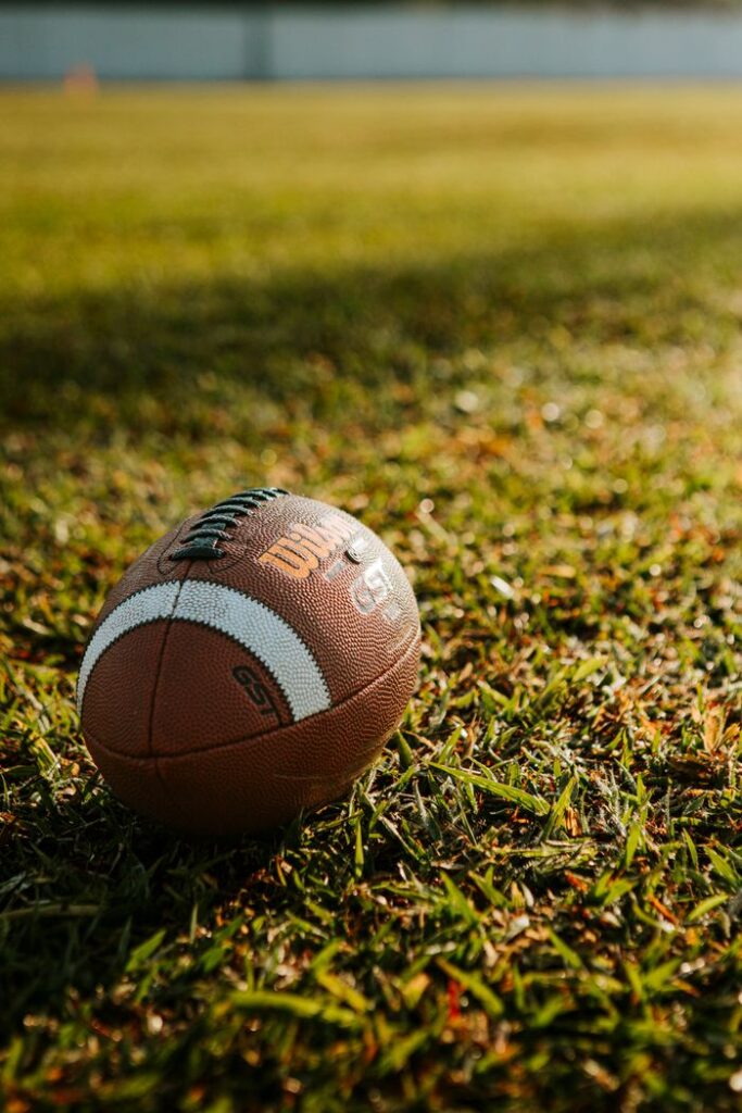 Close-up shot of a football resting on a sunlit grass field, ideal for sports themes.
