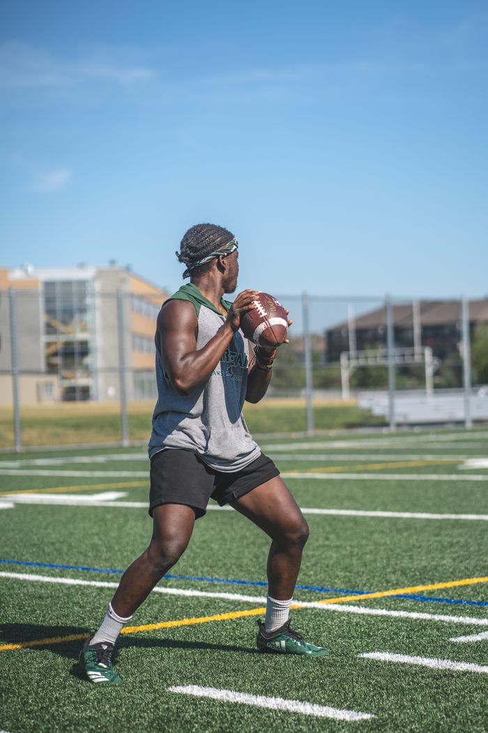 Focused African-American football player practicing on a sunny day in Ottawa, Canada.